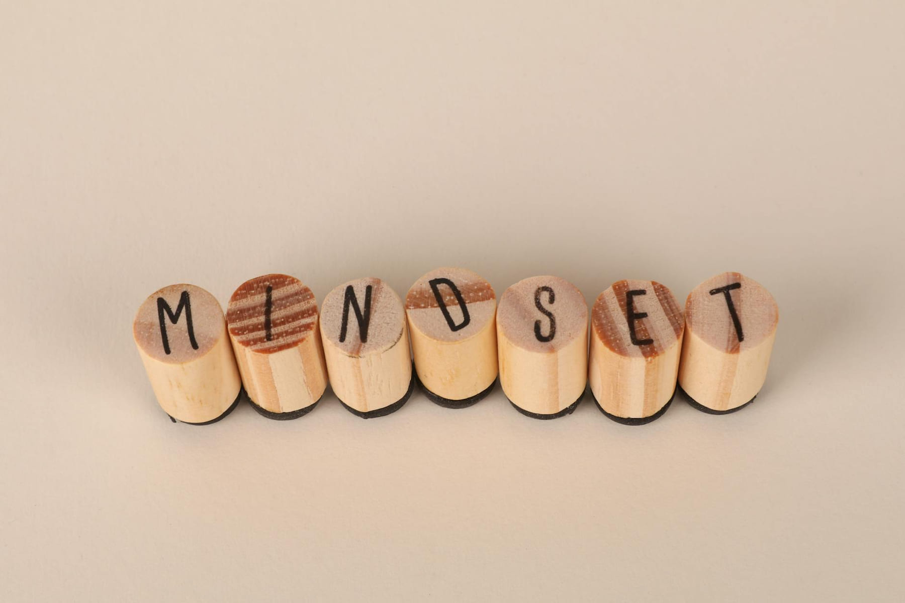 Wooden letter stamps spelling 'Mindset' on a simple beige background, conveying focus and positive thinking. on Inner Progress Project