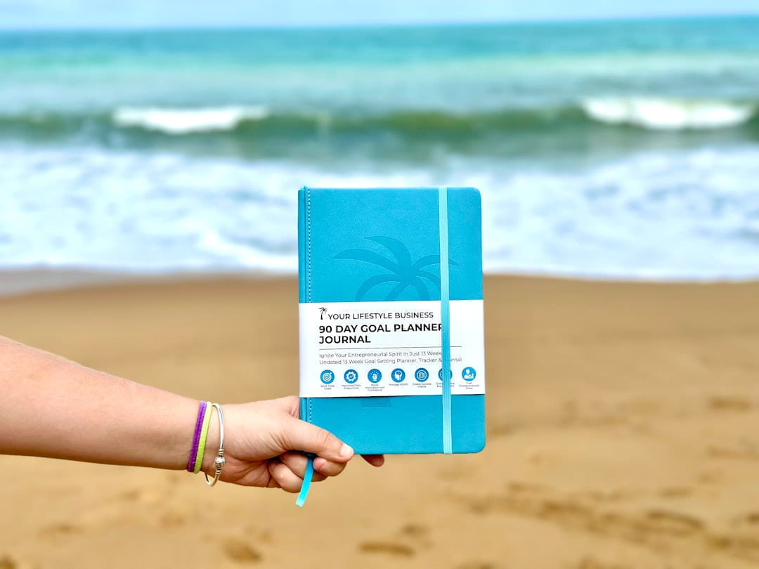a person holding a blue notebook on a beach on Inner Progress Project
