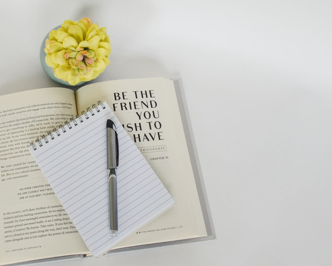 a notebook with a pen on top of it next to a flower on Inner Progress Project