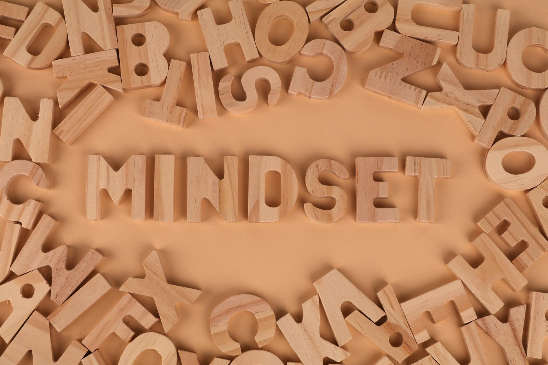 Wooden alphabet letters arranged to spell 'Mindset' on a peach background. on Inner Progress Project