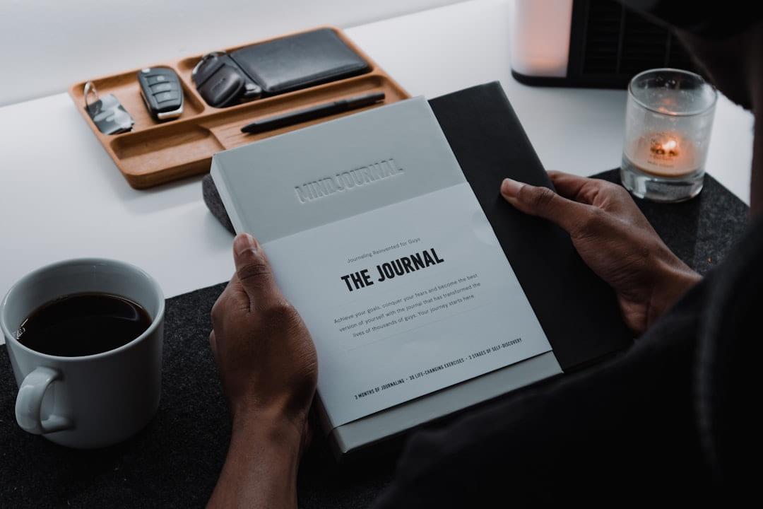 a person sitting at a table with a book and a cup of coffee on Inner Progress Project