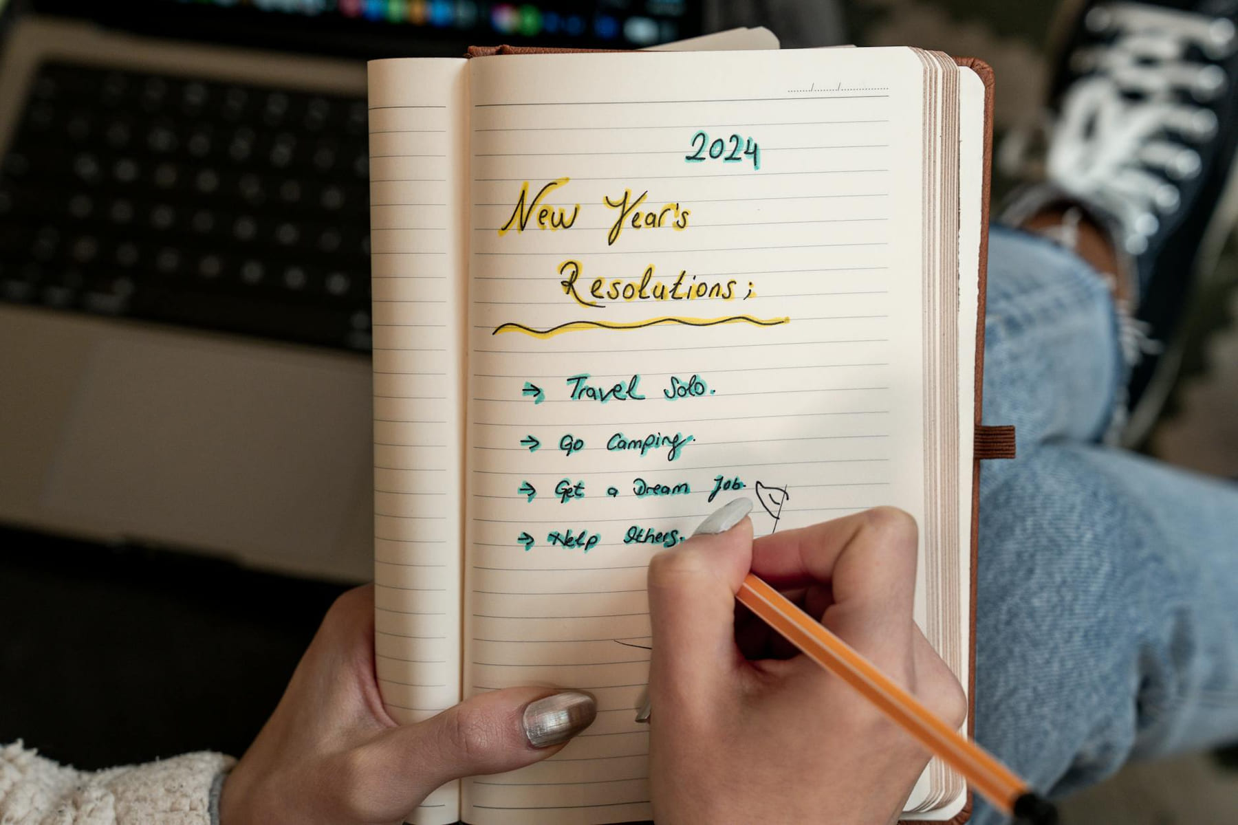 A person writes 2024 New Year's resolutions in a notebook. Concept of planning and personal goals. on Inner Progress Project