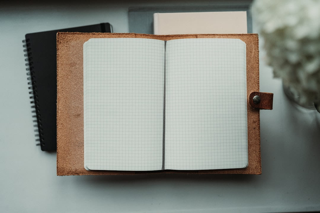 An open notebook sitting on top of a desk next to a flower on Inner Progress Project