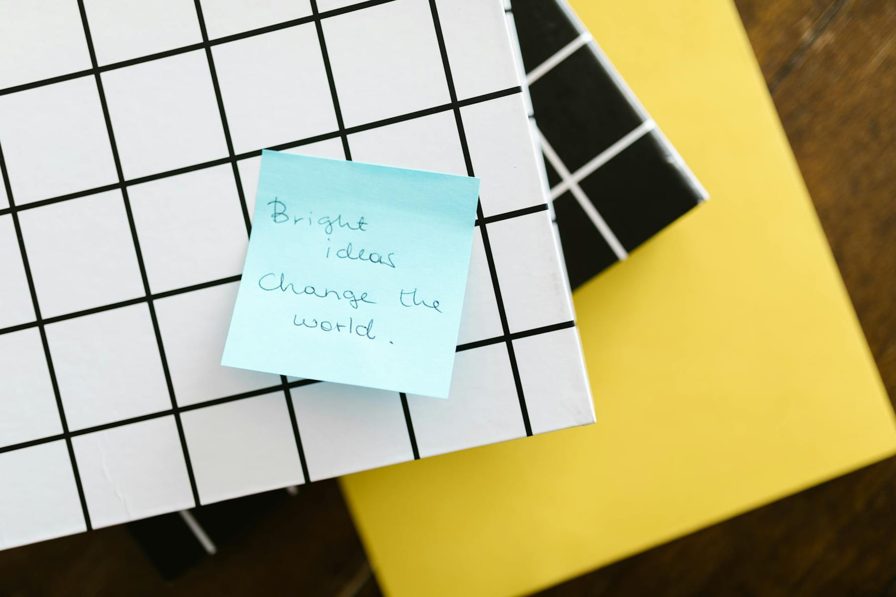 Blue sticky note with motivational quote on grid and solid colored notebooks. on Inner Progress Project